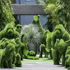 Topiary animals in a manicured garden landscape, including a lion, giraffe, and deer