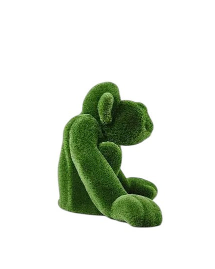 Jubilant, a large seated monkey topiary sculpture in artificial grass, posed with hands on the ground as part of the Guardians Collection.