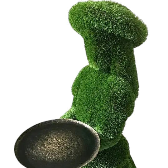 Topiary sculpture of girl in summer hat holding a serving tray, made of artificial grass

