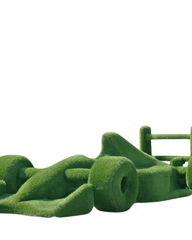 Life-size F1 car sculpture wrapped in artificial grass, designed as a botanical performance piece

