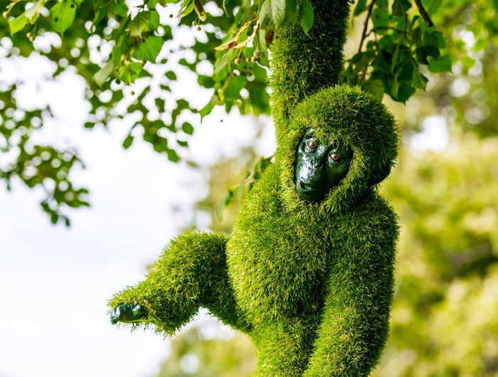 Hanging animal topiary sculpture crafted in lush artificial greenery, blending playfulness and sculptural elegance in a natural outdoor setting